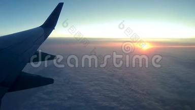 透过飞机的窗户在云层上日落